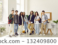 Teacher standing with his students and looking cheerful at camera in the classroom. 132409800