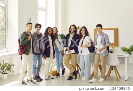Teacher standing with his students and looking cheerful at camera in the classroom. 132409800
