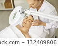 Woman cosmetologist exam young woman skin condition under lamp in beauty spa salon. 132409806
