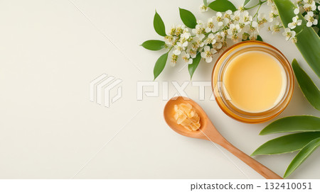 Natural rustic honey jar with hexagonal texture glows linden blossom, wooden spoon lying on table with spoonful acacia flowers , emphasizing theme homemade and organic skin care Natural rustic honey jar with hexagonal texture glows linden blossom, wooden spoon lying on table with spoonful acacia flowers , emphasizing theme homemade and organic skin care 132410051