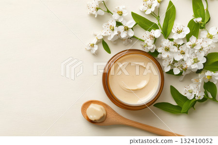 Jar of cream made from natural ingredients with hexagonal texture glows linden blossom, wooden spoon lying on table with spoonful acacia flowers , emphasizing theme homemade and organic skin care Jar of cream made from natural ingredients with hexagonal texture glows linden blossom, wooden spoon lying on table with spoonful acacia flowers , emphasizing theme homemade and organic skin care 132410052