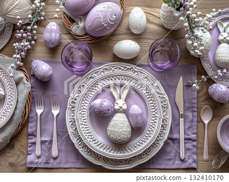 Elegant Easter table setting featuring purple white theme, decorative bunny rabbit centerpiece matching plate. Table adorned with eggs, cutlery, glassware, creating festive atmosphere 132410170