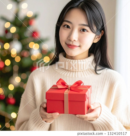 一個穿著紅色針織毛衣的女人打開禮物並微笑,這是一個溫暖的聖誕時刻 一個穿著紅色針織毛衣的女人打開禮物並微笑,這是一個溫暖的聖誕時刻 132410517