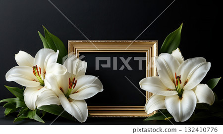 Empty golden frame surrounded by white lilies on a black background, symbolic of remembrance or tribute. 132410776