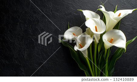 Beautiful bouquet of white calla lilies against a textured black background. Funeral symbol Beautiful bouquet of white calla lilies against a textured black background. Funeral symbol 132410889