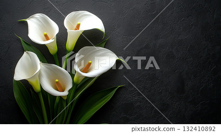 Beautiful bouquet of white calla lilies against a textured black background. Funeral symbol 132410892