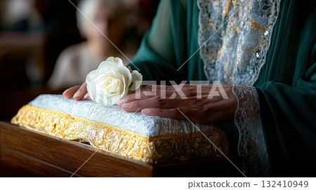 Hand mature woman in mourning attire putting white rose on top closed coffin lid while standing. Mature man in black suit holding one fresh white rose Hand mature woman in mourning attire putting white rose on top closed coffin lid while standing. Mature man in black suit holding one fresh white rose 132410949