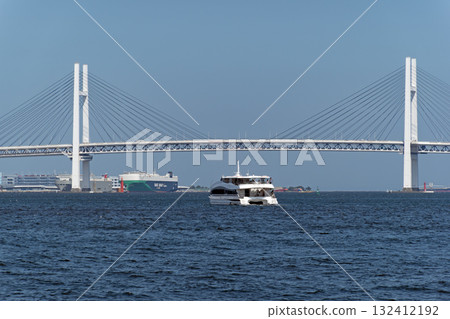 A sightseeing boat crossing the Yokohama Bay Bridge under a blue sky 132412192