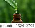 Drop dripping from aloe vera leaf into glass bottle, symbolizing health care. 132412794