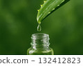 Drop dripping from aloe vera leaf into glass bottle, symbolizing health care. 132412823