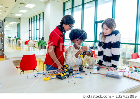 Multiracial teen boy explain about how to assemble the robot and discuss with the girls in public library. 132412899
