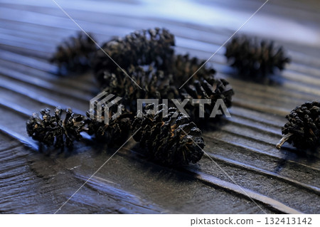Small aspen cones are scattered on a wooden table Small aspen cones are scattered on a wooden table 132413142