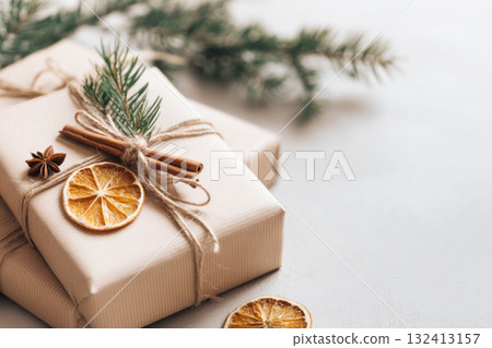 Wrapped gifts with natural decorations including dried orange slices, cinnamon sticks, and fir branches, creating a festive holiday atmosphere Wrapped gifts with natural decorations including dried orange slices, cinnamon sticks, and fir branches, creating a festive holiday atmosphere 132413157