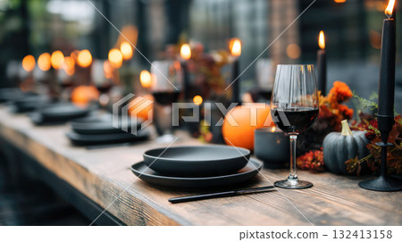 Elegant dining table set for autumn celebration, featuring black plates, wine glasses, candles, pumpkins, and a warm, inviting atmosphere for gatherings Elegant dining table set for autumn celebration, featuring black plates, wine glasses, candles, pumpkins, and a warm, inviting atmosphere for gatherings 132413158