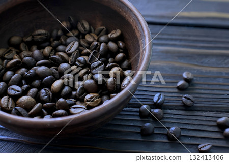 Coffee beans in a clay pot and a few beans scattered on a wooden table Coffee beans in a clay pot and a few beans scattered on a wooden table 132413406