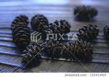 Several aspen cones are scattered on a wooden table Several aspen cones are scattered on a wooden table 132413407