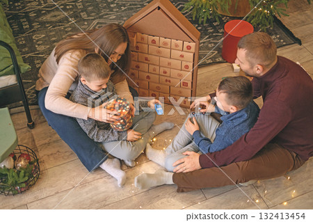Children and their parents open Christmas presents at home on the living room floor on Christmas morning Children and their parents open Christmas presents at home on the living room floor on Christmas morning 132413454