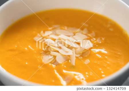 Pumpkin soup puree decorated with almond flakes in white bowl closeup Pumpkin soup puree decorated with almond flakes in white bowl closeup 132414709