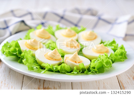 light snack of hard boiled chicken eggs and mayonnaise on a white table. light snack of hard boiled chicken eggs and mayonnaise on a white table. 132415290