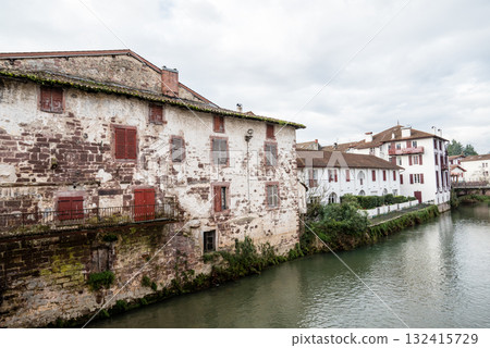 Historic buildings and trees along the river in the morning mist in Saint-Jean-Pied-de-Port, Basque Country, France 132415729