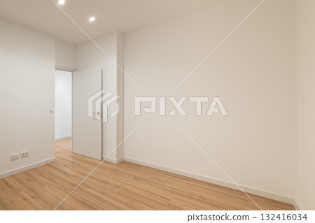 Empty room with white walls and wooden floor. Two doors visible on the left side. Bright lighting enhances the spacious feel. 132416034