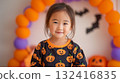 秋天，穿著南瓜印花襯衫和萬聖節裝飾，在室內歡笑的小女孩 132416835
