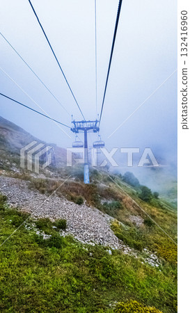 A ski lift ride in the mountains in the fog 132416960