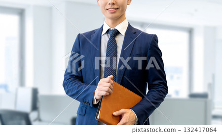 Smiling male businessman holding a binder 132417064