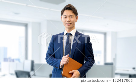 Smiling male businessman holding a binder 132417065