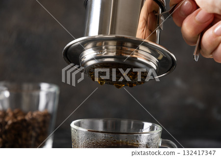 Brew Vietnamese coffee with sweet condensed milk in glass cup by traditional method on black background. Close up. 132417347