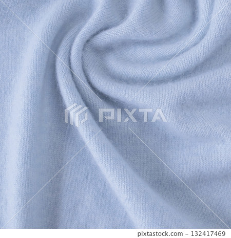 Blue cashmere fabric, textile is folded, knitwear texture, natural fabric, top view. Soft light blue fabric texture with soft folds. Blue cashmere fabric, textile is folded, knitwear texture, natural fabric, top view. Soft light blue fabric texture with soft folds. 132417469