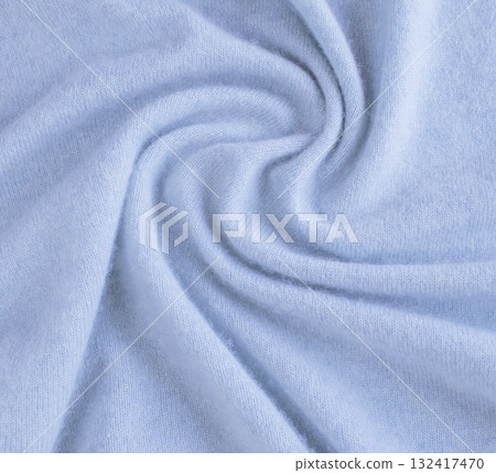 Blue cashmere fabric, textile is folded, knitwear texture, natural fabric, top view. Soft light blue fabric texture with soft folds. 132417470