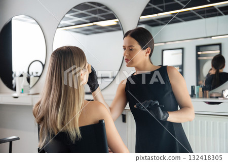 Makeup artist applies cosmetics to client at modern beauty studio during daylight hours Makeup artist applies cosmetics to client at modern beauty studio during daylight hours 132418305