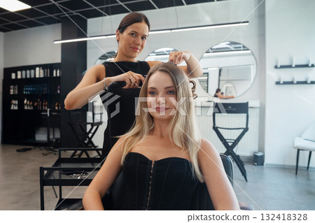 Woman receives a stylish hair treatment in a modern salon setting during daylight hours Woman receives a stylish hair treatment in a modern salon setting during daylight hours 132418328