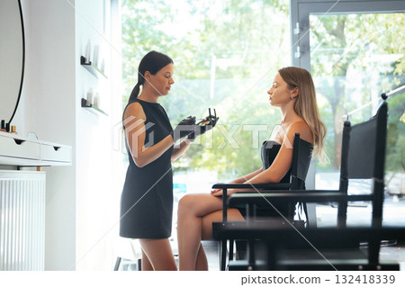 Beauty professional applies makeup in a modern salon setting during a bright daytime session Beauty professional applies makeup in a modern salon setting during a bright daytime session 132418339