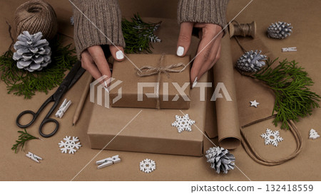 Woman packing Christmas gifts in brown paper Woman packing Christmas gifts in brown paper 132418559