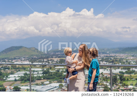 Mother with his two sons standing in front of Popocatepetl volcano in Mexico, surrounded by clouds, enjoying a scenic family adventure and breathtaking outdoor view Mother with his two sons standing in front of Popocatepetl volcano in Mexico, surrounded by clouds, enjoying a scenic family adventure and breathtaking outdoor view 132419268