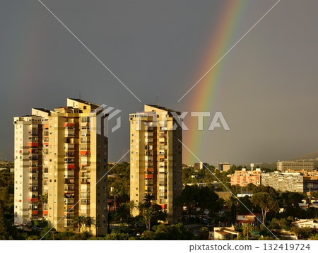 rainbow hues adorn sleek skyscrapers, stylish towers reflect warm colors against stormy urban sky rainbow hues adorn sleek skyscrapers, stylish towers reflect warm colors against stormy urban sky 132419724