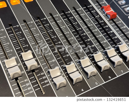 Close-up of audio mixer faders with control panel and light indicators. Professional sound equipment, studio recording and precision in music production. Close-up of audio mixer faders with control panel and light indicators. Professional sound equipment, studio recording and precision in music production. 132419851