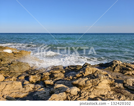 serene rocky coastline bathed in warm glow, peaceful seaside landscape with gentle waves and soft 132420102