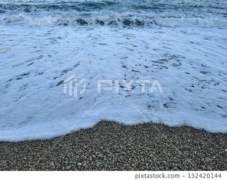 incoming wave collides with pebbles and spray, dynamic ocean waves breaking on pebble beach incoming wave collides with pebbles and spray, dynamic ocean waves breaking on pebble beach 132420144