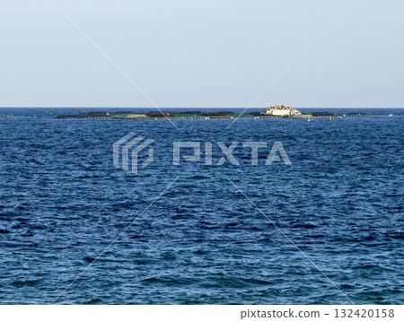 vast blue waters and distant rocky islet, open sea stretching beyond with cliffy island on horizon 132420158