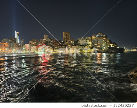 vibrant waterfront reflections shimmer brightly, colorful lights dance over lively seaside scene 132420227