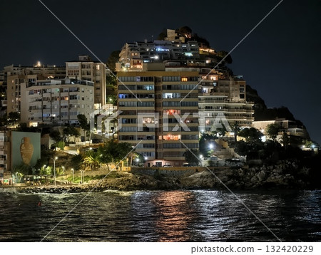 night seascape reflections, serene night seascape with shimmering city reflections and silhouettes 132420229