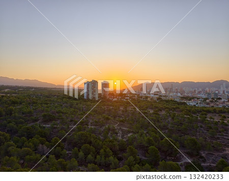 twilight casts warm glow overlooking city, evening sunset behind forest and urban landscape twilight casts warm glow overlooking city, evening sunset behind forest and urban landscape 132420233