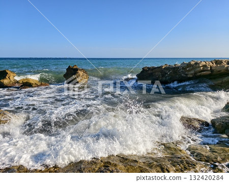 vivid blue sea dynamically breaking against textured rocks with energetic spray and vibrant movement vivid blue sea dynamically breaking against textured rocks with energetic spray and vibrant movement 132420284