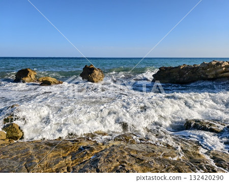 calm sea with rocks and horizon view, gentle ocean waves reach rocky shoreline under distant sky 132420290