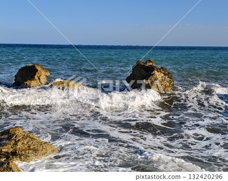 sea splashes violently on rocks, powerful sea waves crash forcefully against rugged rocks 132420296