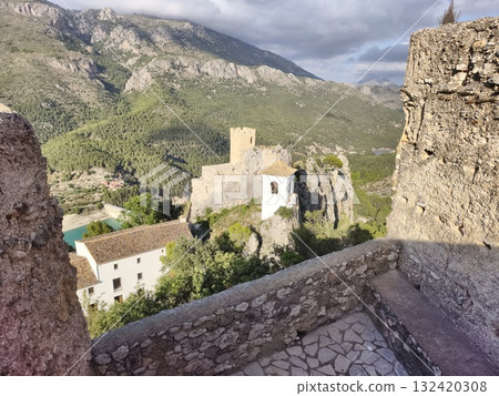castle overlooks valley scenery, ancient castle on hill with panoramic valley views under sunny sky 132420308