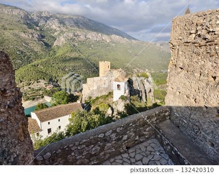 ancient stone fortress perched above emerald reservoir with sweeping hillside views and heritage 132420310